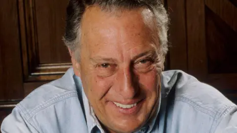 Getty Images Frederick Forsyth, wearing a pale blue shirt, smiling at the camera