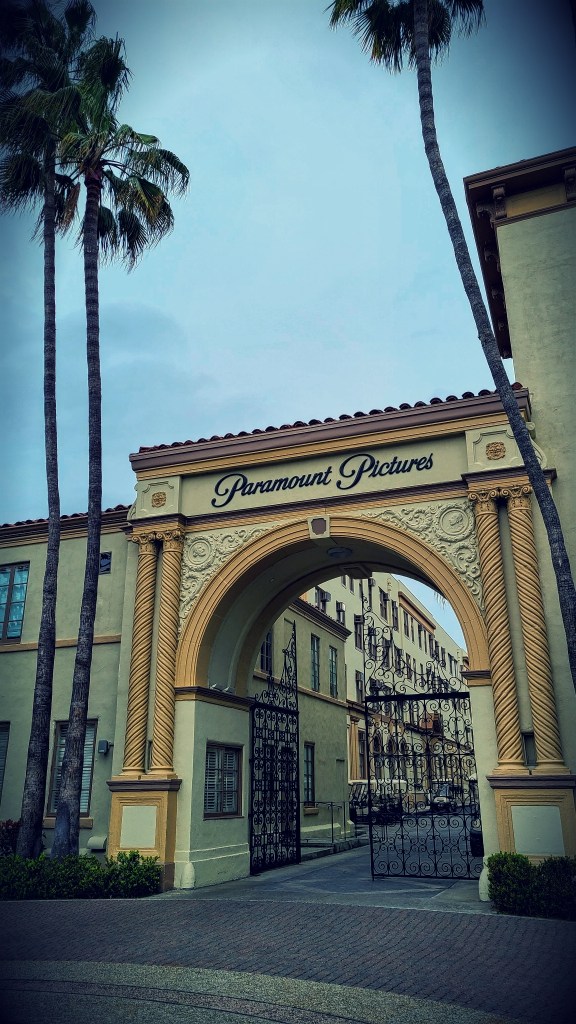 Paramount Pictures' famous entrance is a yellow, old fashioned gateway with "Paramount Pictures" at the top, while surrounded by palm trees.