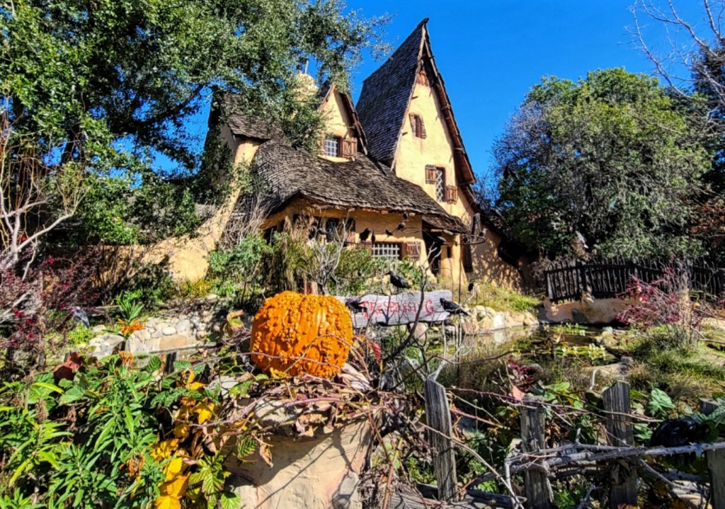 The Spadena House, also known as The Witch's House, is a storybook house in Beverly Hills, California. Crooked yellow house with thatched roof and pumpkins.